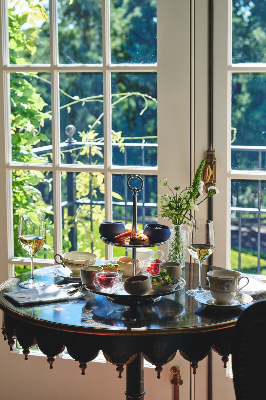 Tiered tasting bites and white wine on an antique table by tall French windows at the Jordan chateau