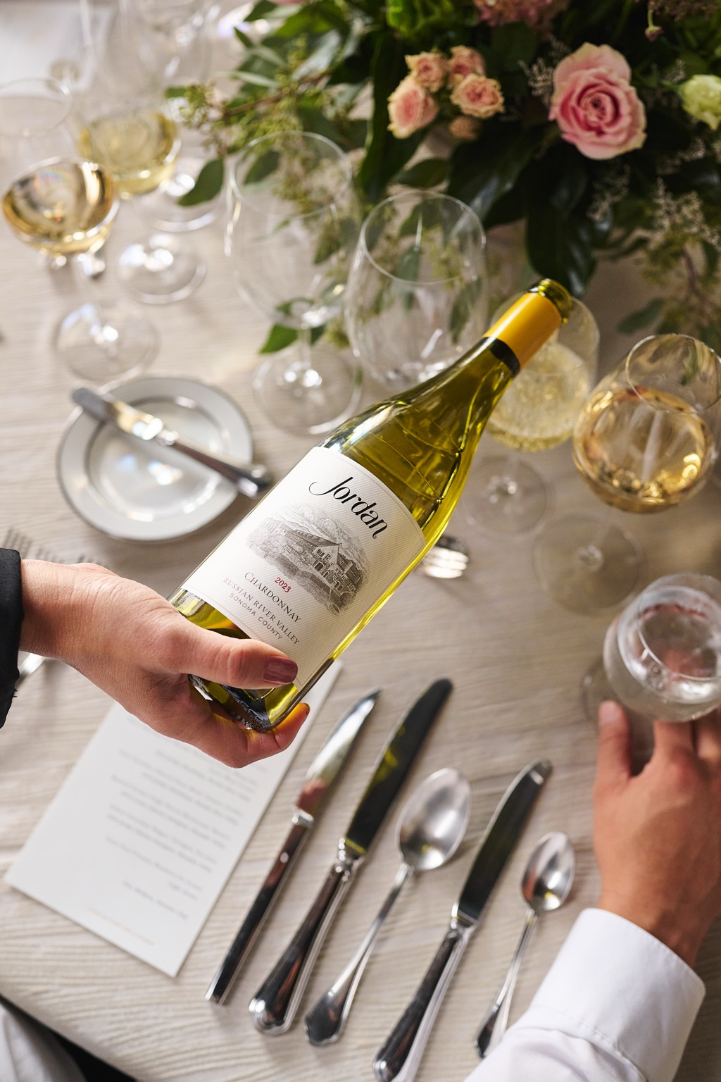 Jordan chardonnay presented over a set dinner table with pink roses at the Alexander Valley winery