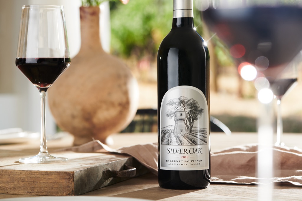 Close-up of Silver Oak 2019 Alexander Valley cabernet sauvignon on a set table with glasses of red