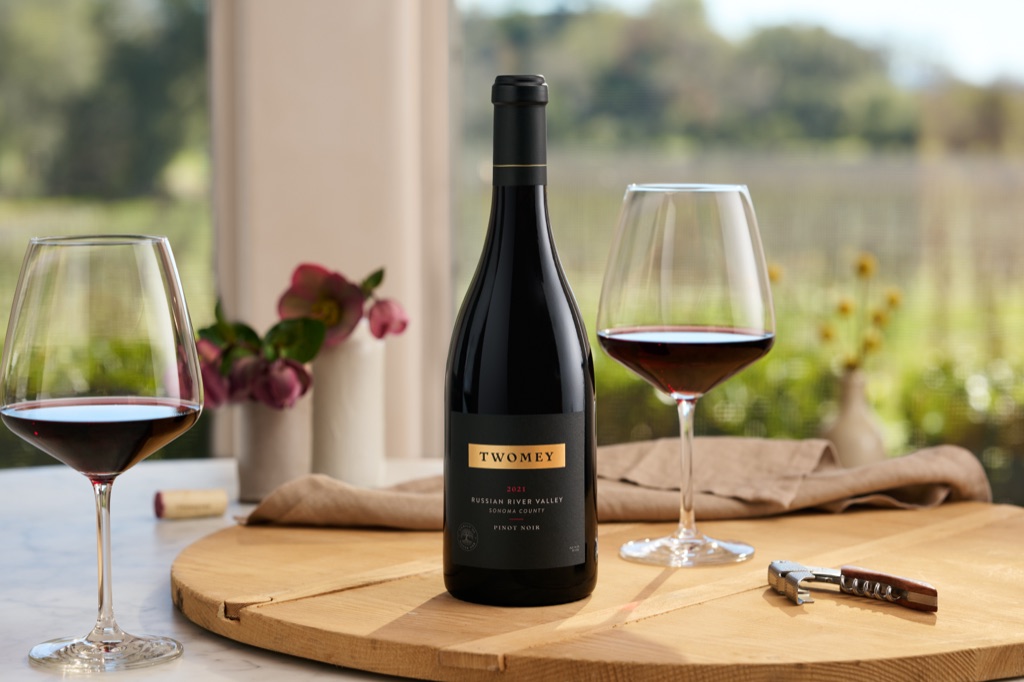 Twomey Russian River Valley pinot noir with two glasses on a wood board, vineyard light through the tasting room window