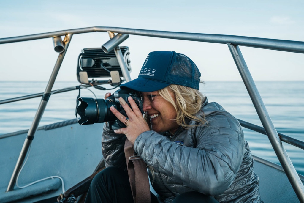 Dawn Heumann smiling behind the camera on the bow of a fishing boat at sea