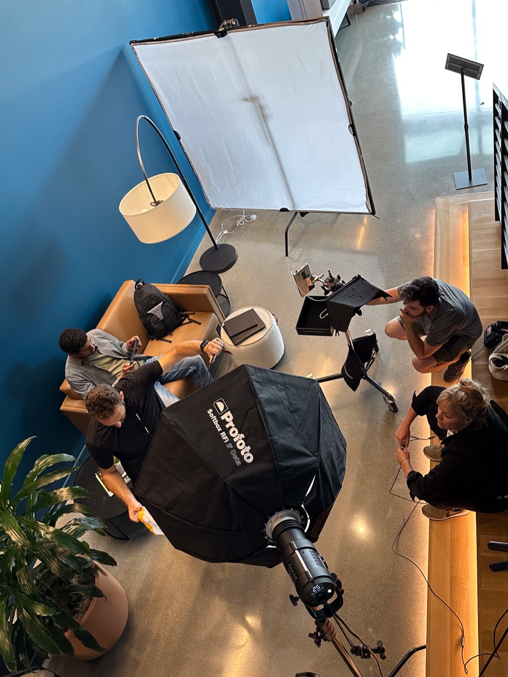 Softbox and crew around a lounge interview set seen from the mezzanine above