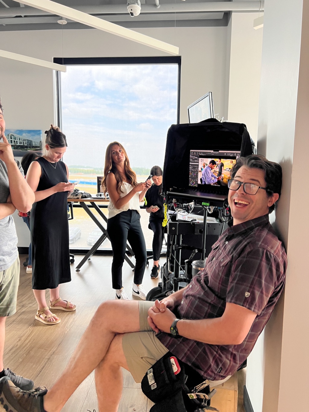 Crew cracking up beside the monitor on an office interview set