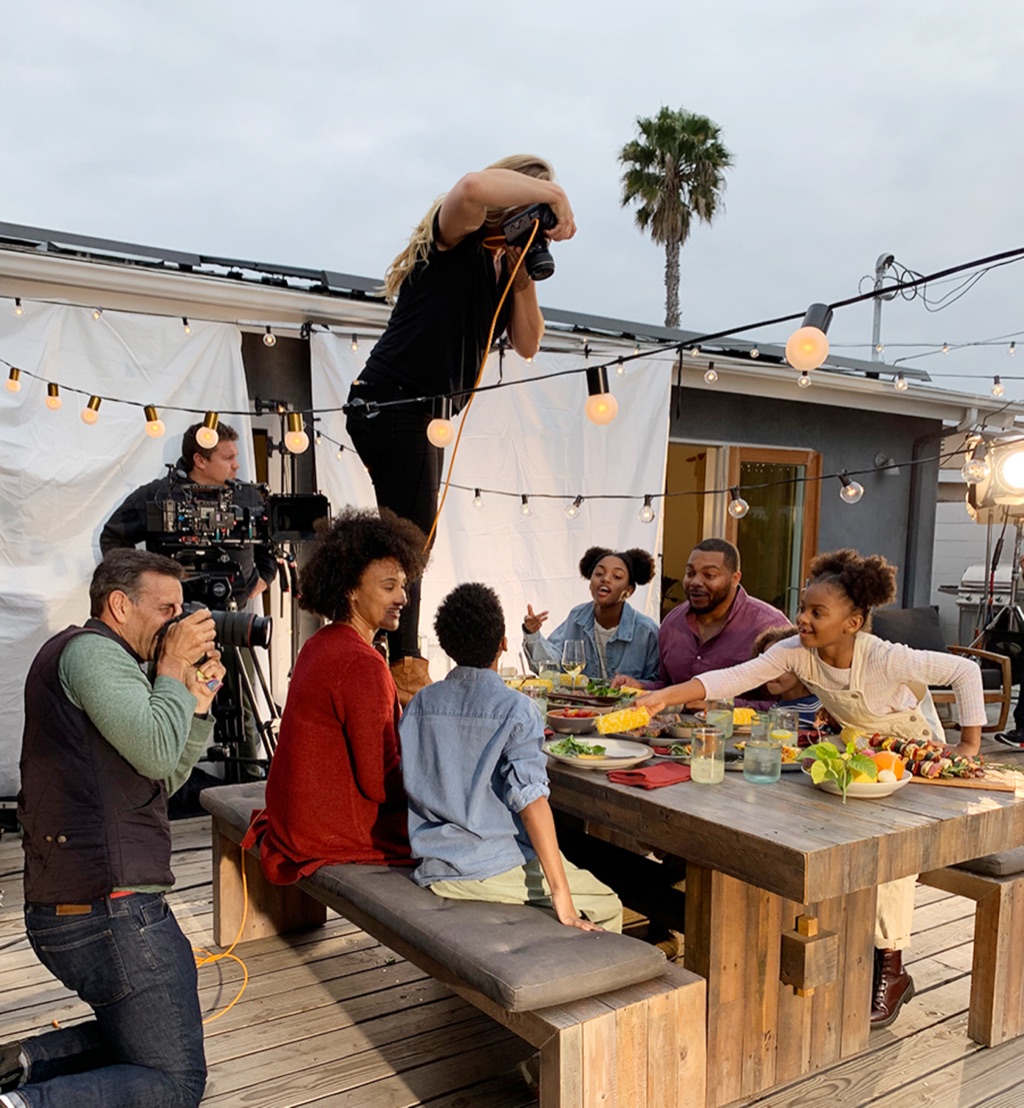 Dawn Heumann shooting a rooftop family dinner from a platform above the string lights
