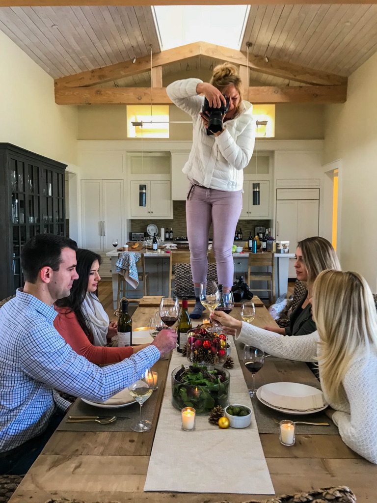 Dawn Heumann standing on the dining table to shoot a holiday tablescape from directly above