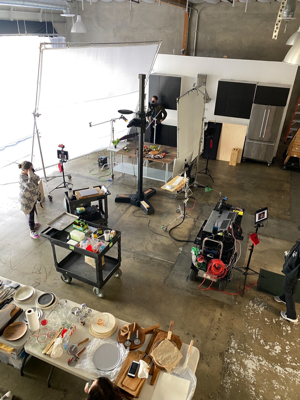 Studio food set seen from above with an overhead camera rig, prop carts, and crew at work