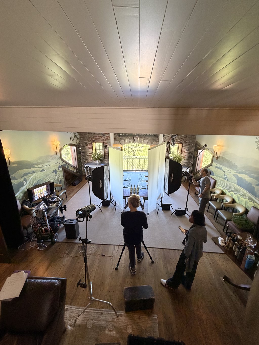 Overhead view of a commercial wine shoot built inside a winery tasting room, with V-flats, softboxes, and a tethered monitor station