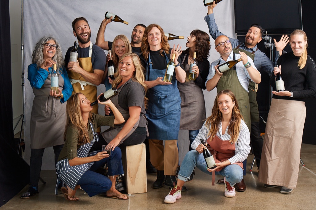 A winery team hamming it up with bottles for a playful group portrait on set