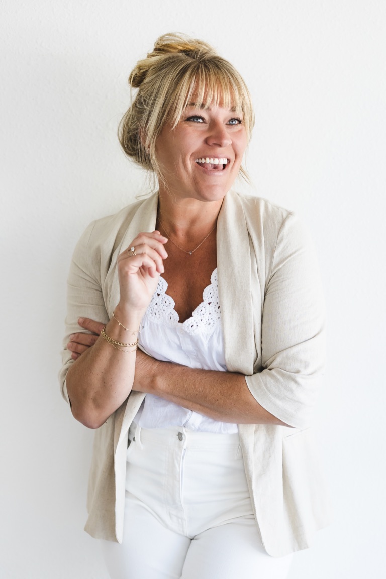 Dawn Heumann, Sonoma County commercial photographer and director, laughing in a linen blazer against a white wall