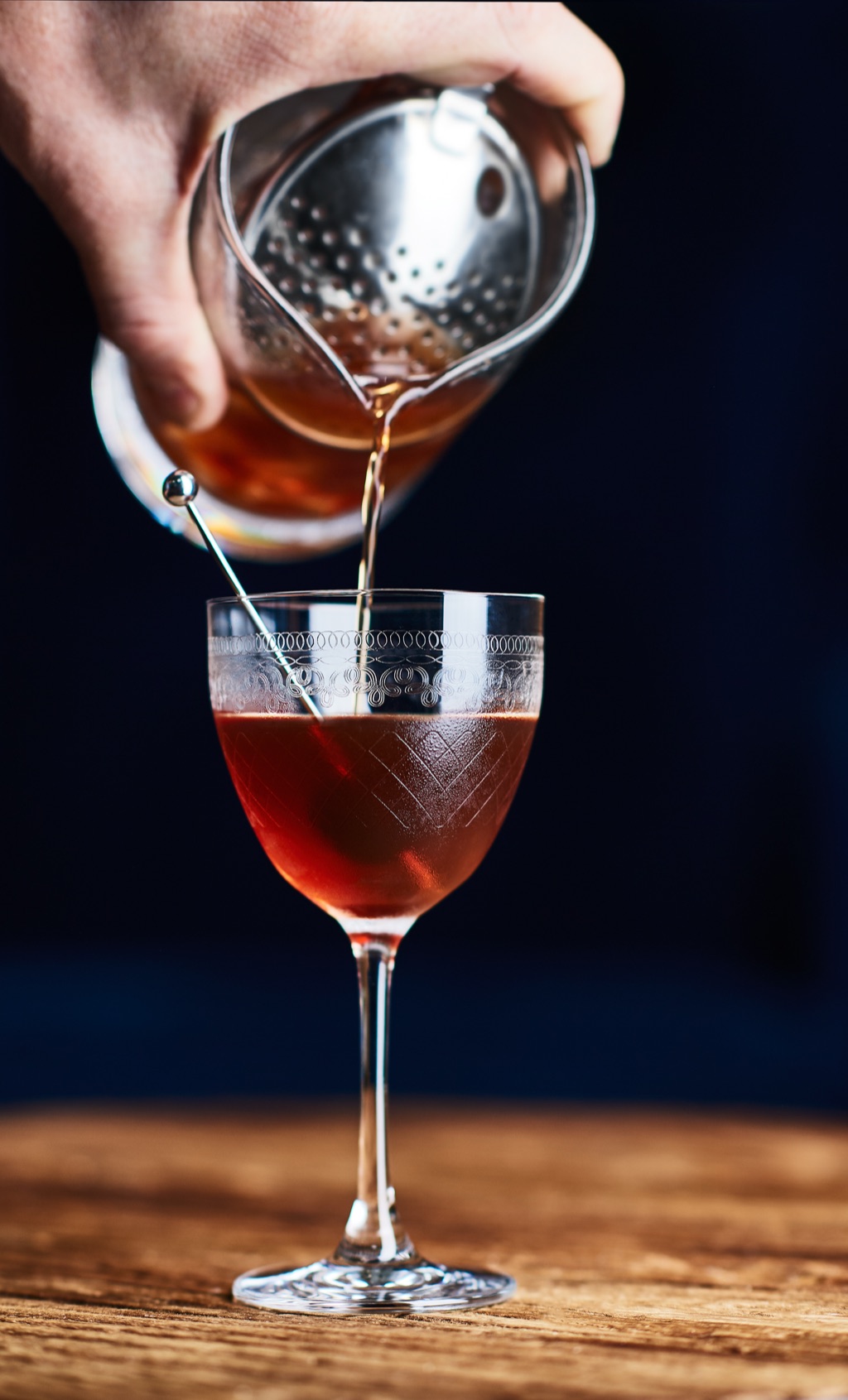 Manhattan strained into an etched nick and nora glass against deep blue