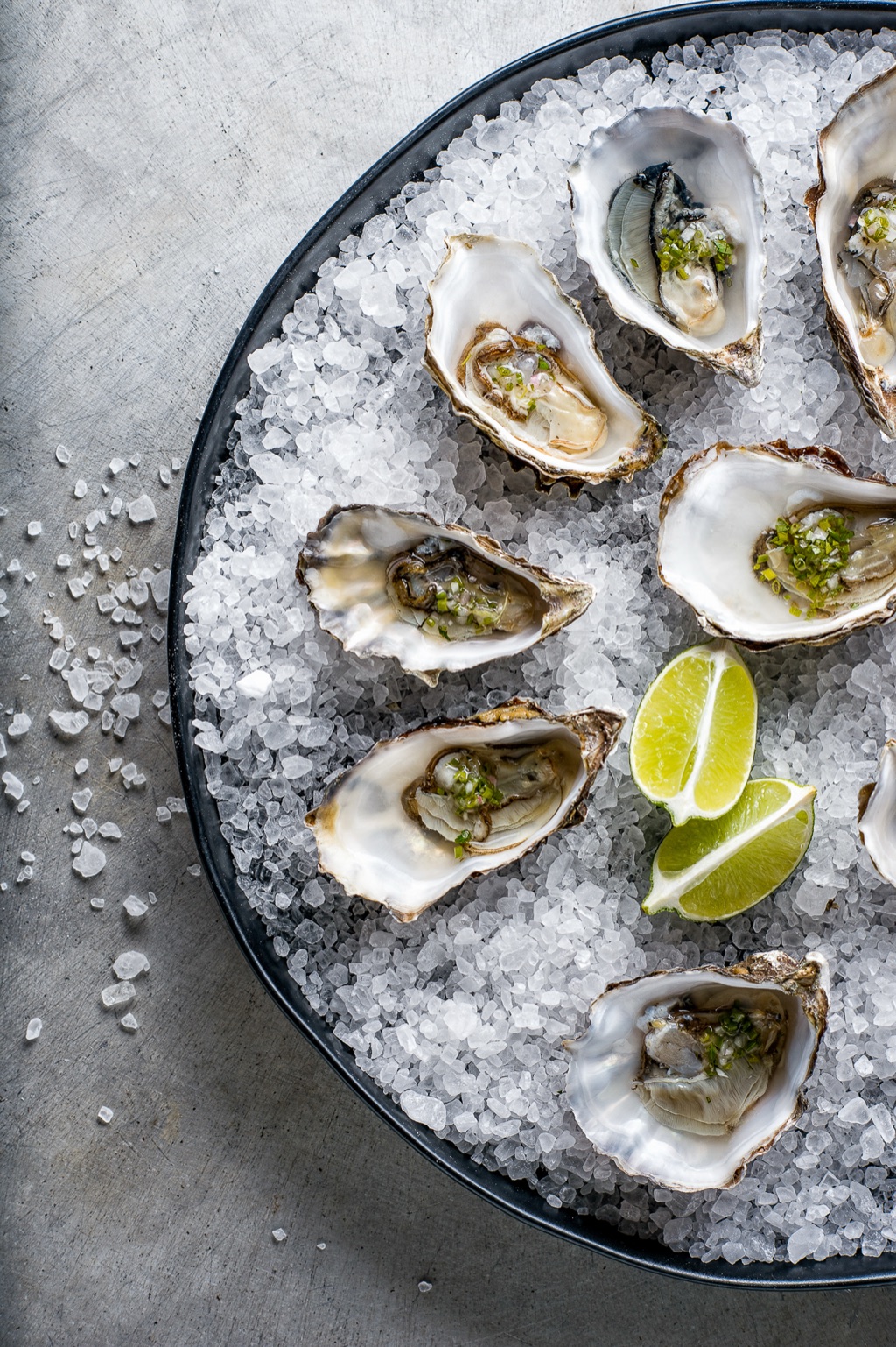 Overhead of oysters with mignonette and lime on a platter of rock salt