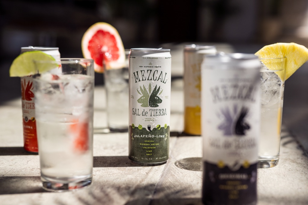 Sal de Tierra canned mezcal cocktails in the sun with lime, grapefruit and pineapple garnishes