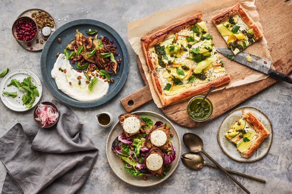 Overhead spread of zucchini puff pastry tart, labneh with grilled figs and goat cheese toasts