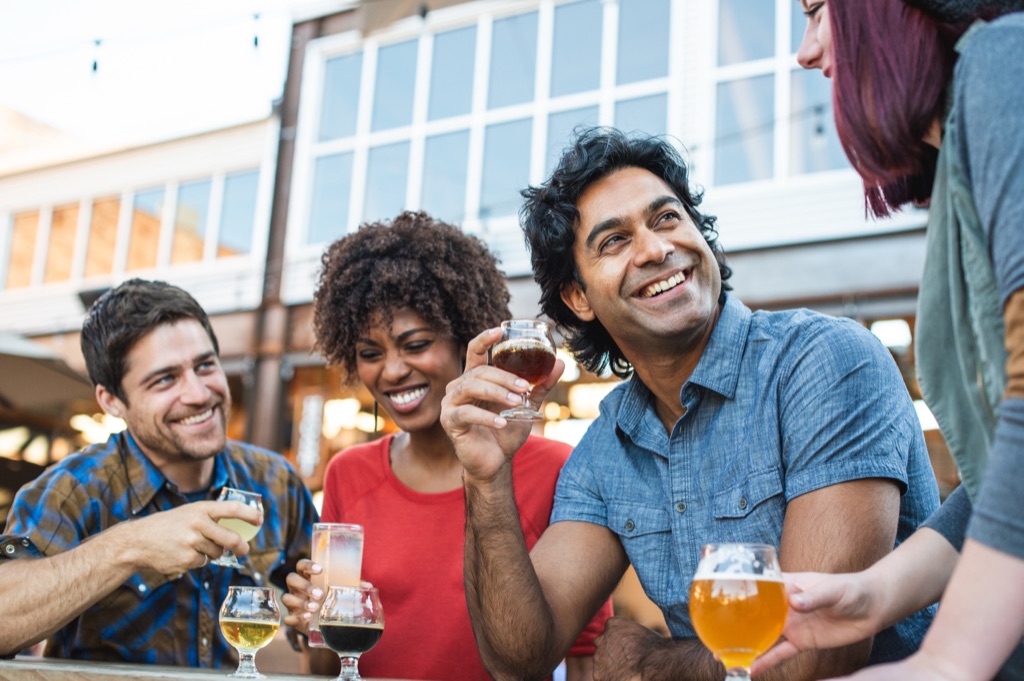 Four friends sampling craft beer taster glasses outside a brewery