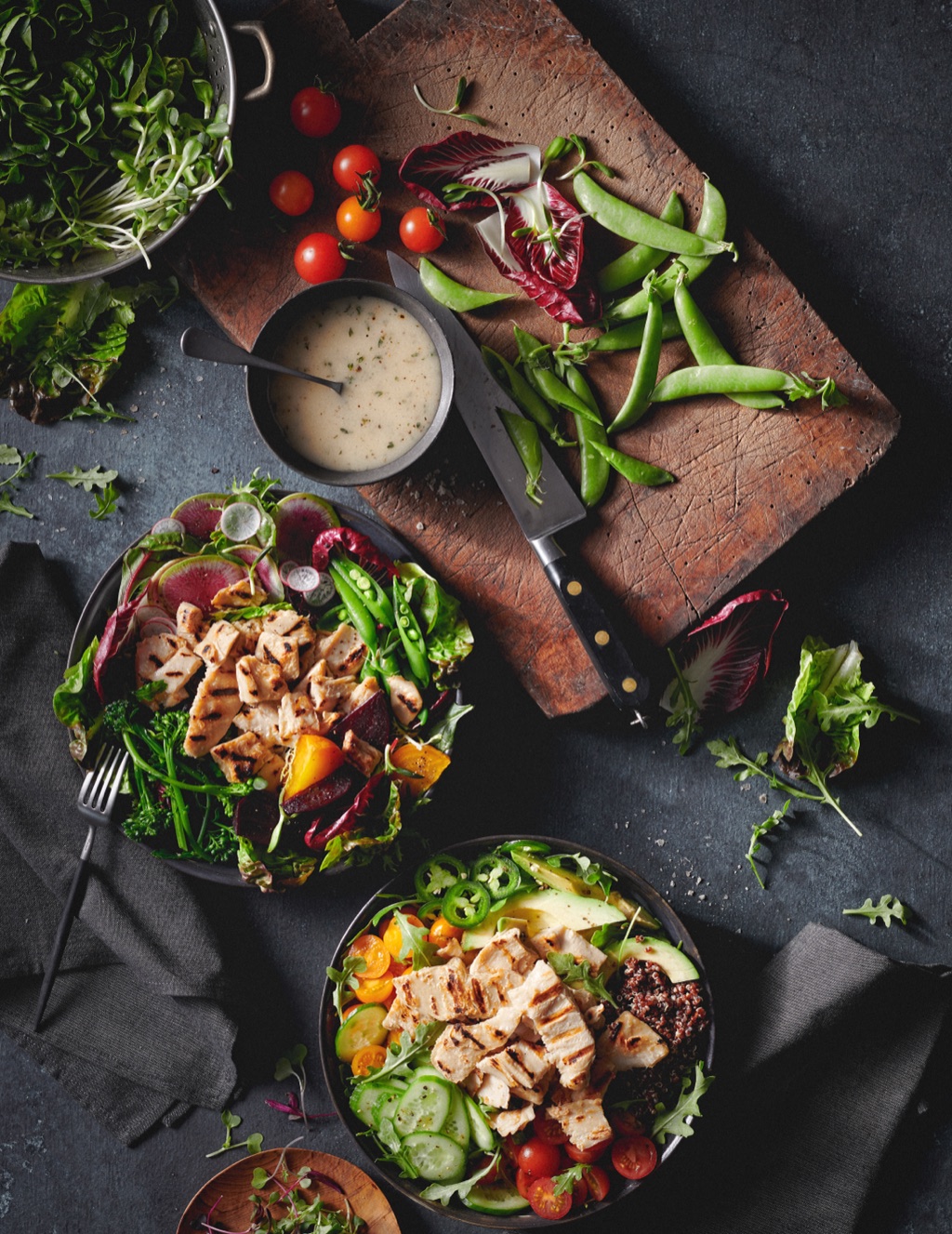 Dark moody overhead of two plant based grilled chicken salads with snap peas and radicchio