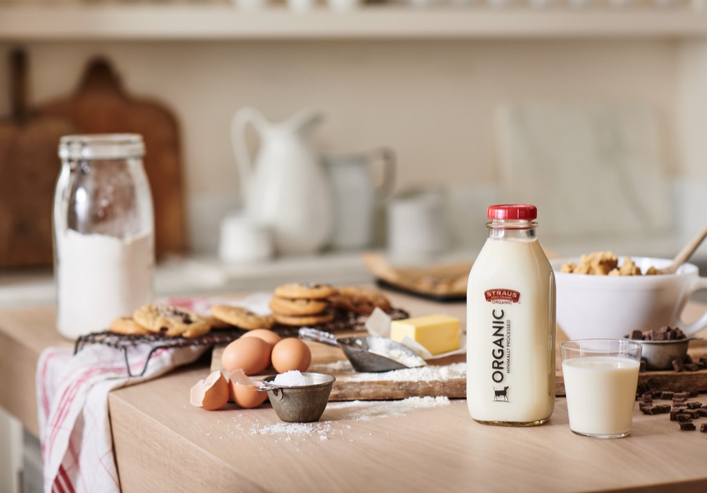 Straus Family Creamery organic milk bottle with chocolate chip cookies, eggs, and butter in a baking scene