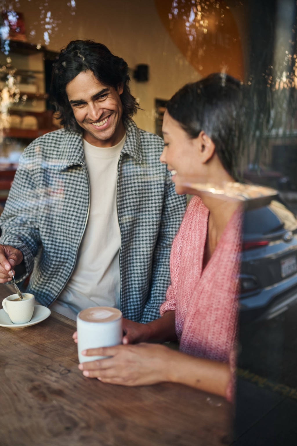 Couple laughing over coffee at a cafe window counter
