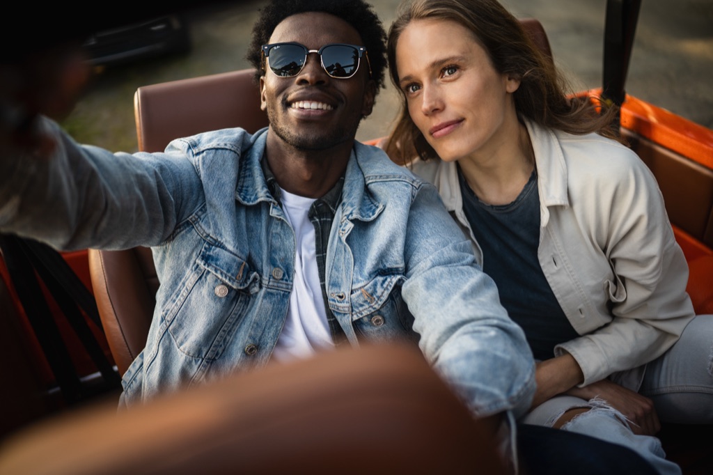 Couple sitting close in a vintage truck, the man grinning in sunglasses