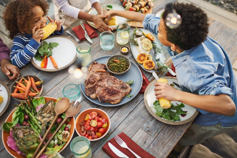Overhead of a family sharing a grilled dinner outdoors, a still from a reel directed by Dawn Heumann