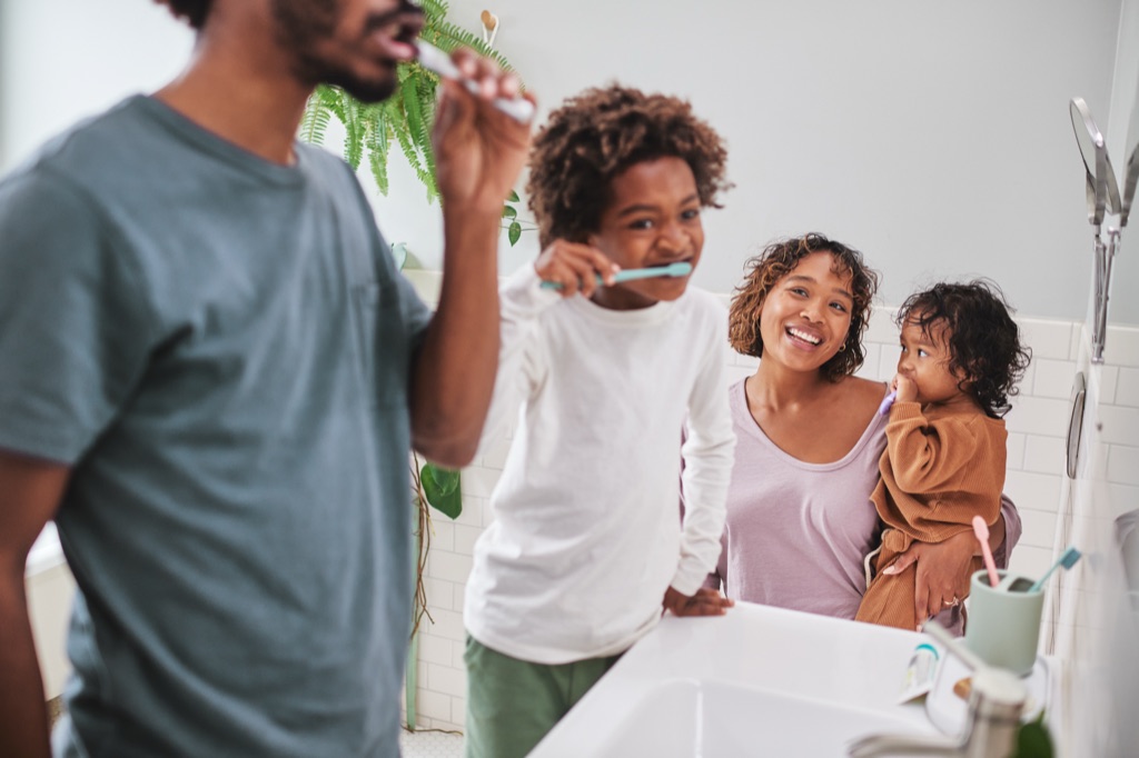 Family of four brushing teeth together at the bathroom sink