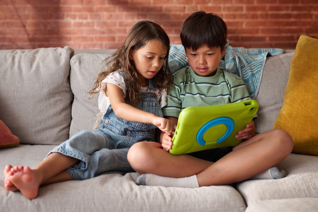 Girl and boy sharing a kids tablet together on a couch