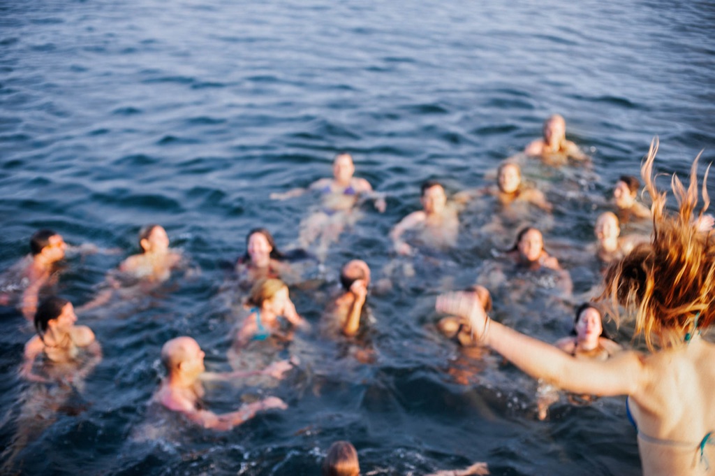 Documentary frame of a crowd of swimmers laughing in a dark blue ocean