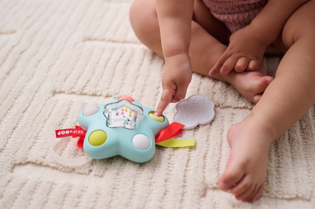 Baby finger pressing a star shaped Skip Hop activity toy
