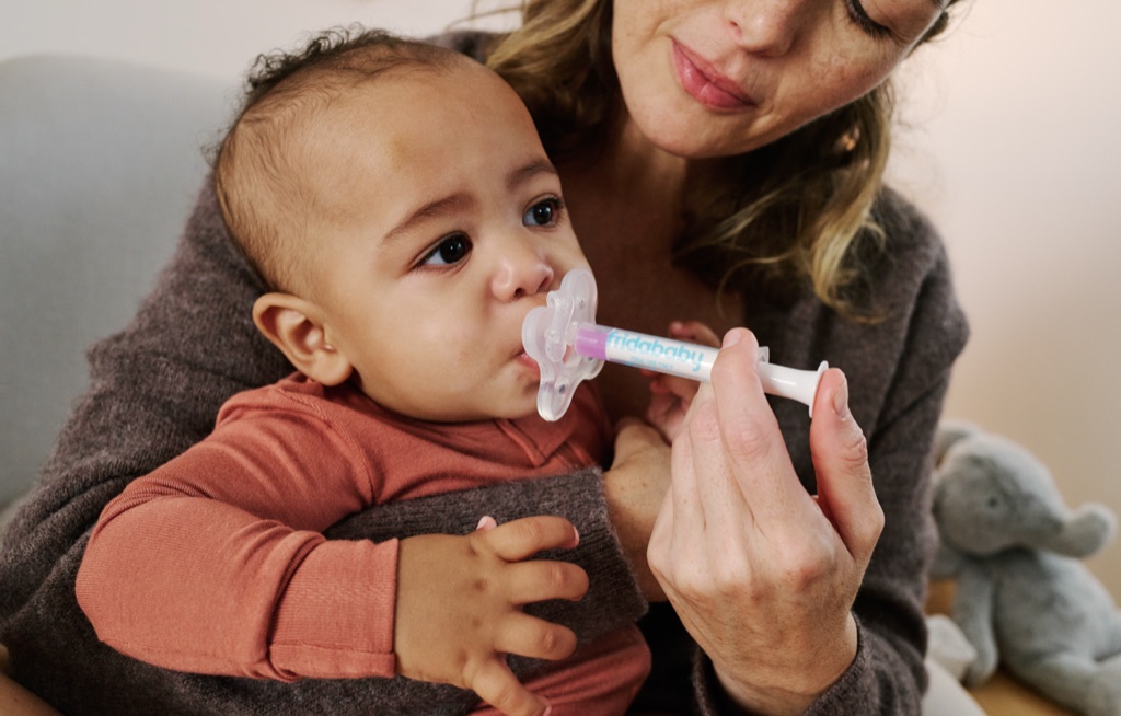 Mom giving her baby medicine with a Fridababy pacifier medicine dispenser