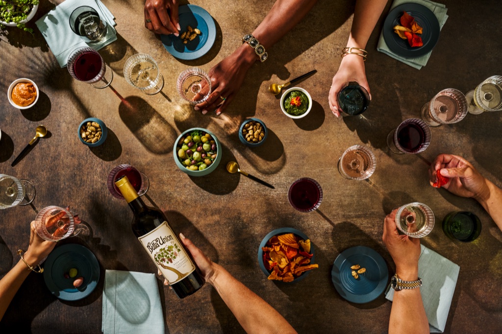 Overhead of Bella Union Napa Valley cabernet held over a snack table of olives, chips and rose glasses