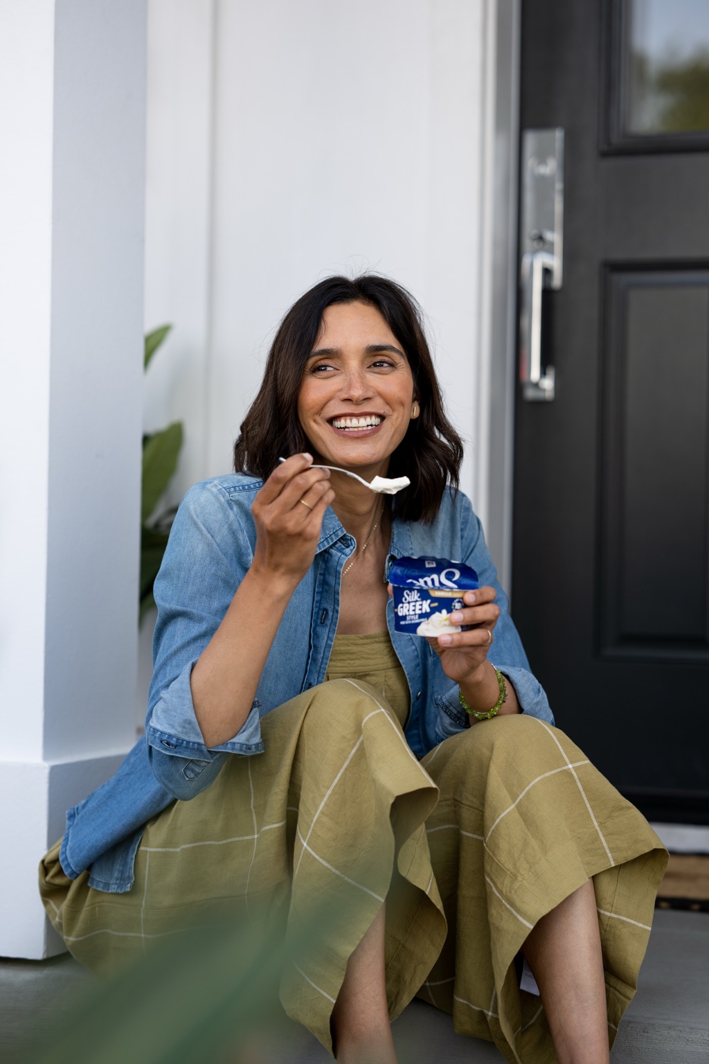 Woman enjoying Silk Greek Style yogurt on her front steps