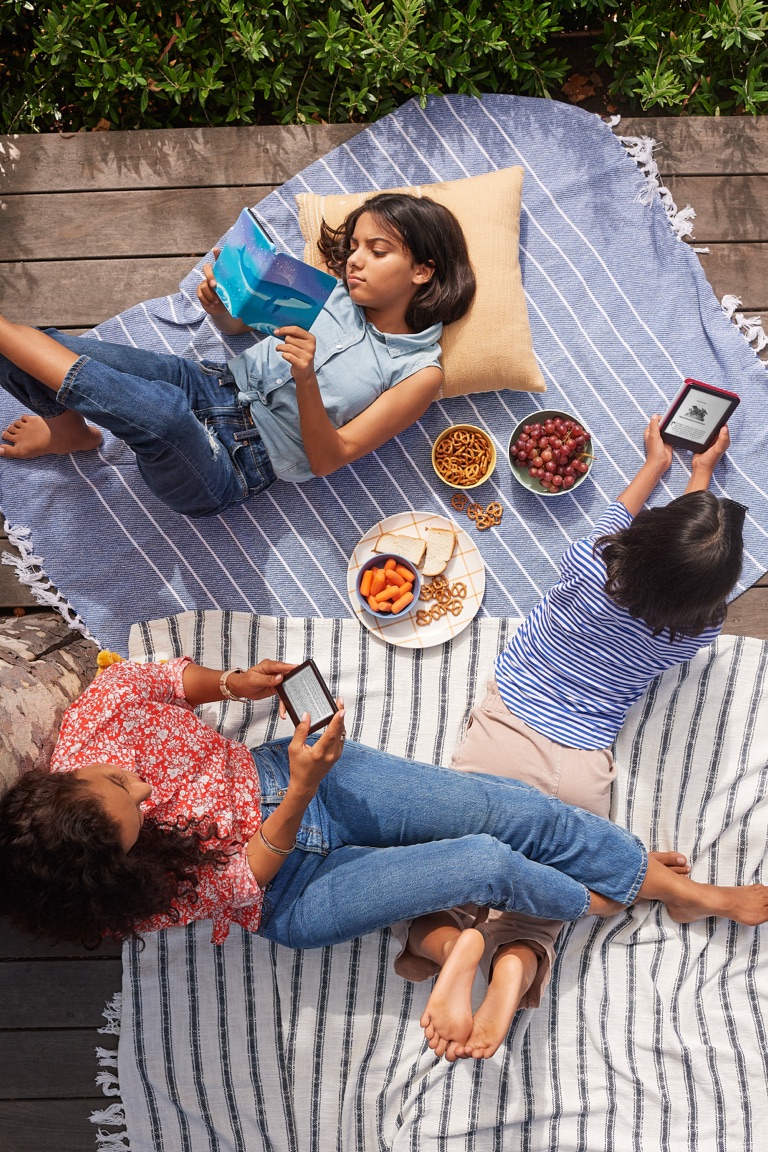Overhead view of a family reading Kindles on striped picnic blankets with snacks, Amazon Kindle campaign, photographed by Dawn Heumann