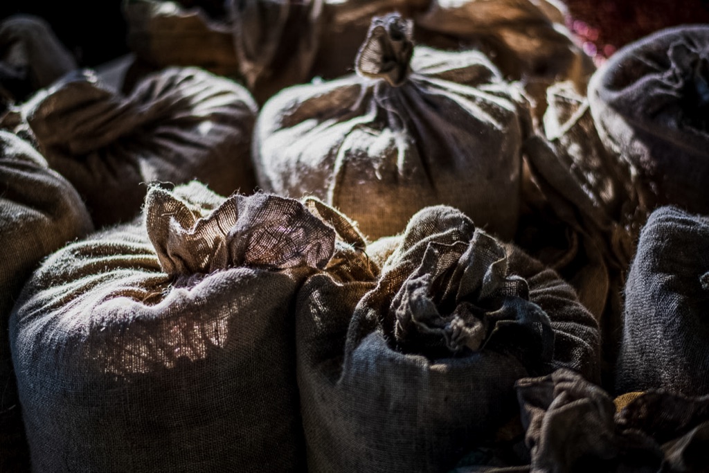 Tied sacks of coffee catching a shaft of warehouse light