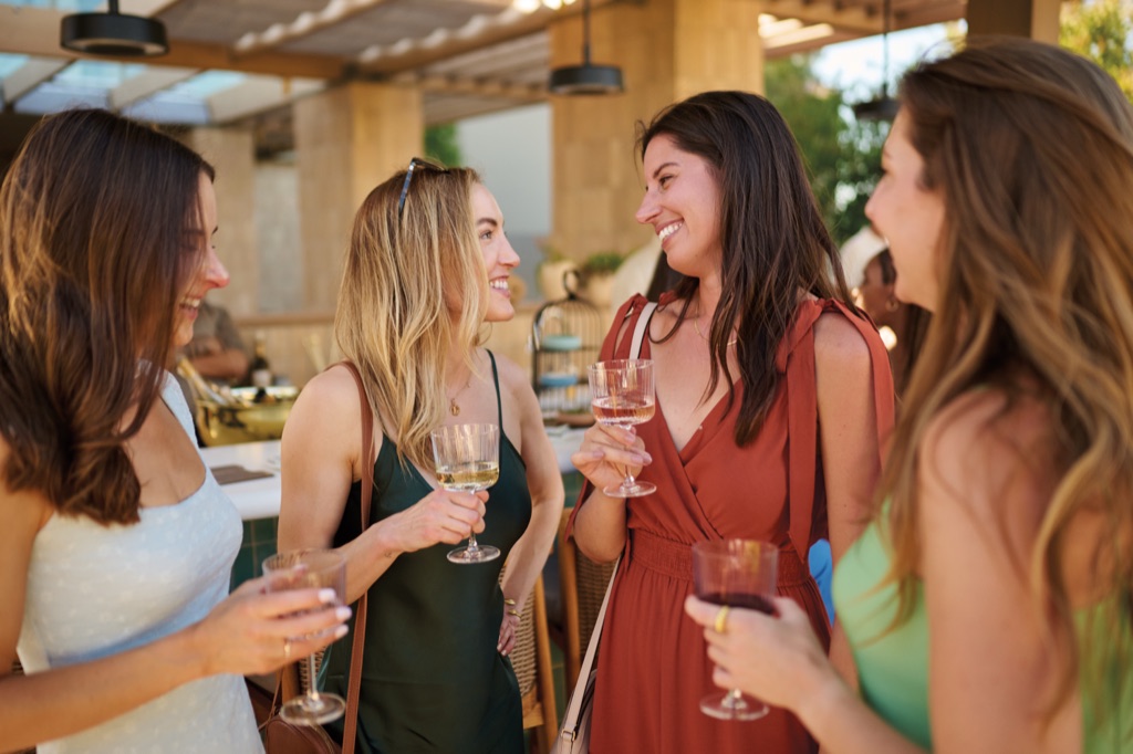 Four women chatting over glasses of wine and rose near the outdoor tasting bar