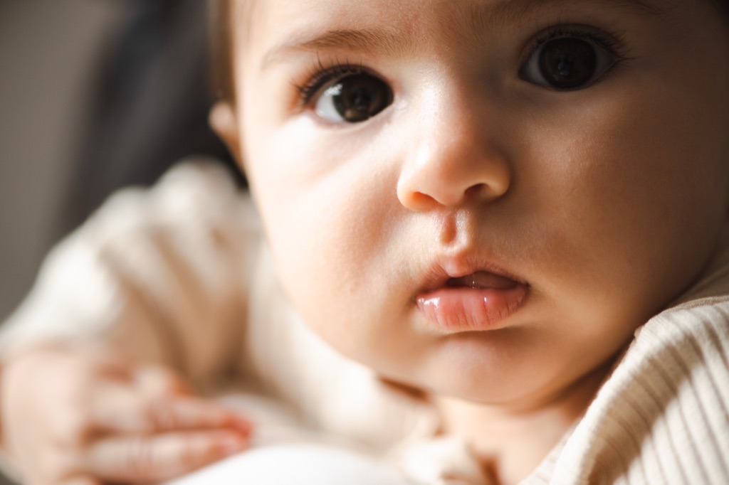 Close-up of a brown-eyed baby resting in a parent's arms, ByHeart infant formula campaign, photographed by Dawn Heumann
