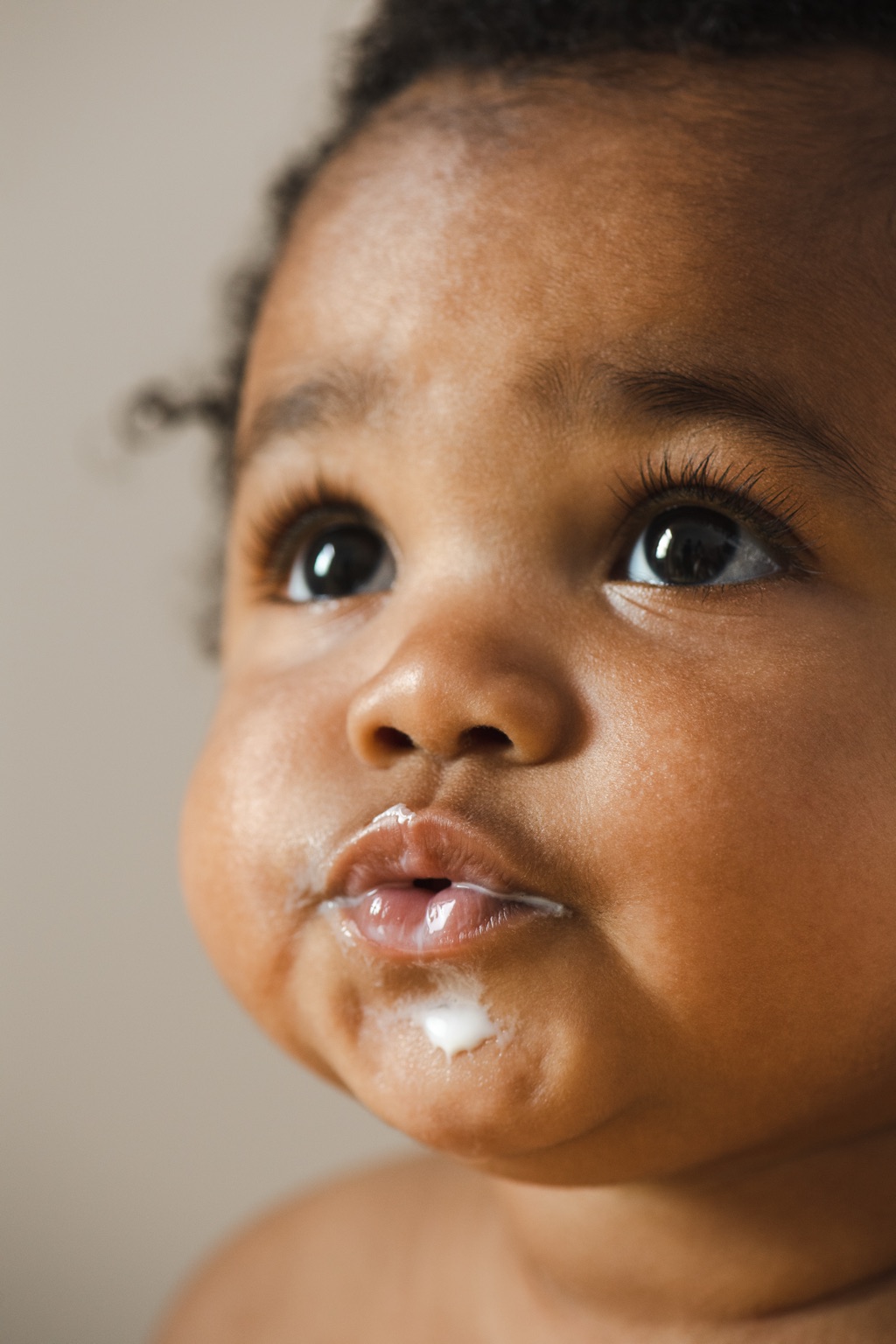 Profile of a baby looking up with milk on their lips and chin, ByHeart campaign detail