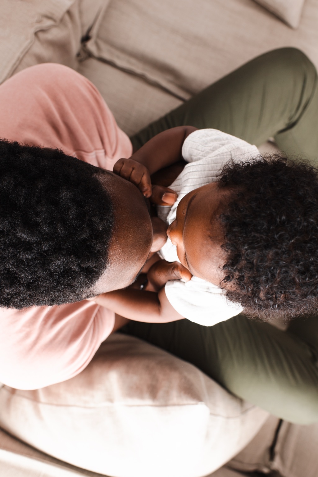 Overhead view of a father cuddling his baby close on the couch, ByHeart lifestyle photography