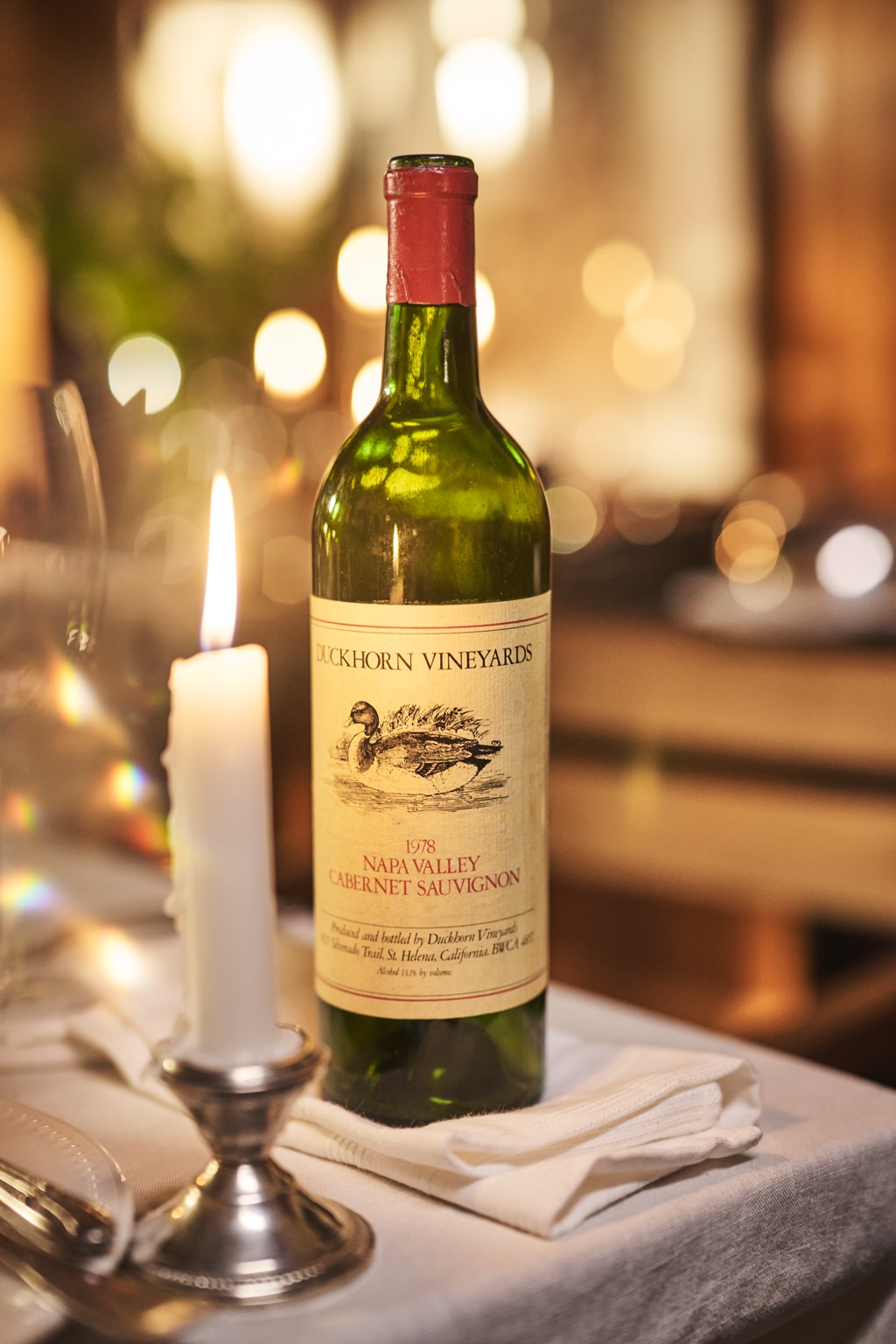 Vintage 1978 bottle of Duckhorn Vineyards Napa Valley Cabernet Sauvignon beside a lit taper candle
