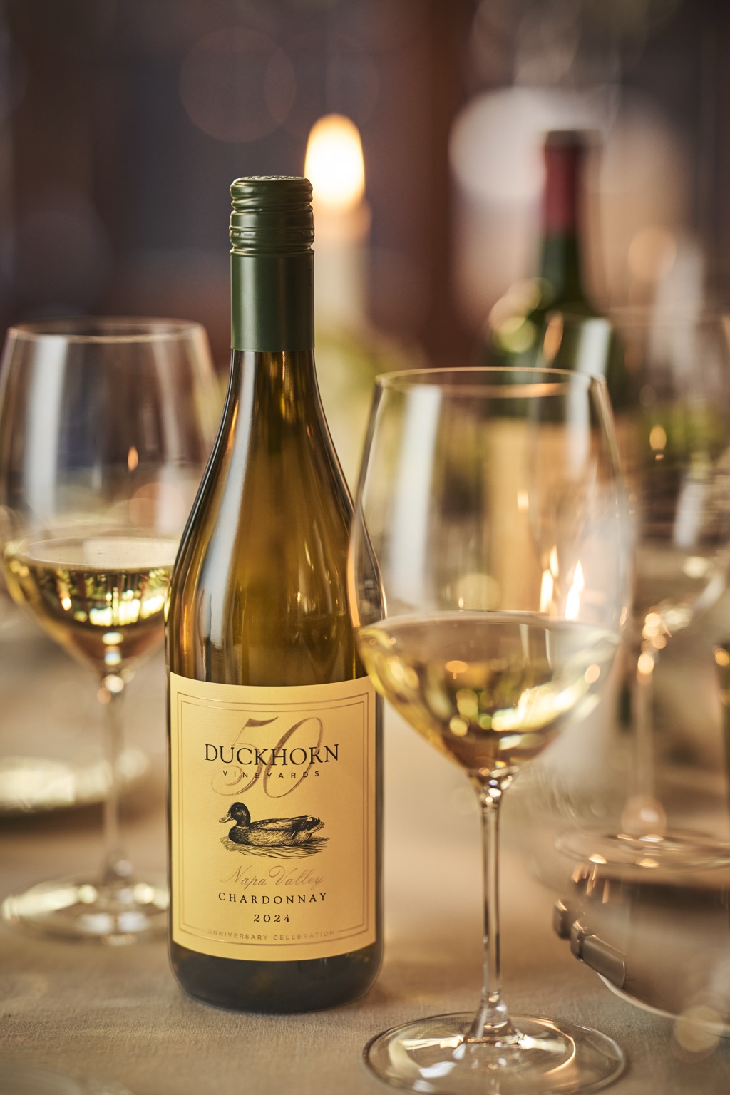 Bottle of Duckhorn Napa Valley Chardonnay beside a poured glass in warm candlelight