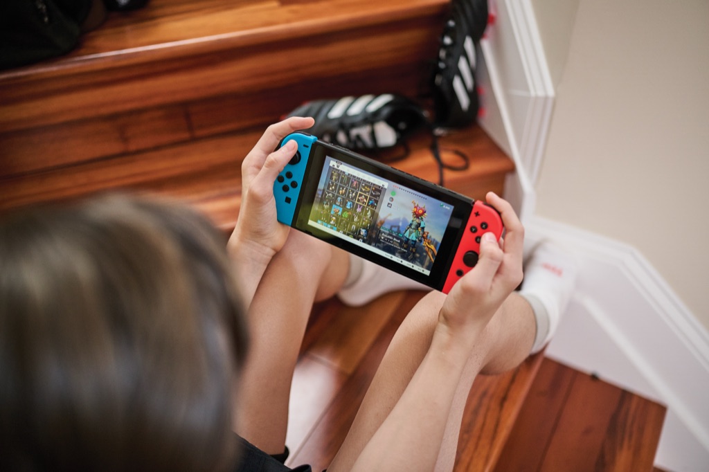Boy sitting on the stairs playing an adventure game on a handheld console