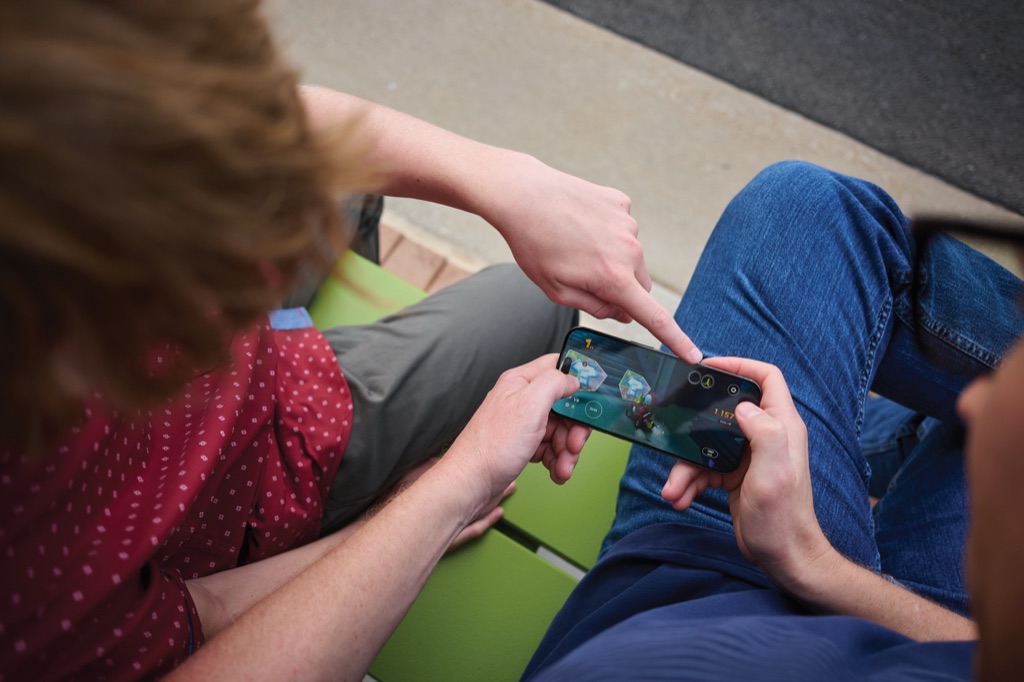 Overhead view of two friends playing a kart racing game on a phone outside