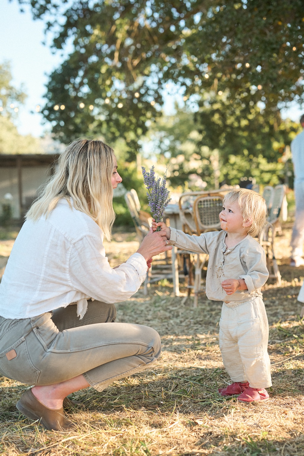 Woman handing a bouquet of fresh lavender to a toddler at a farm dinner gathering