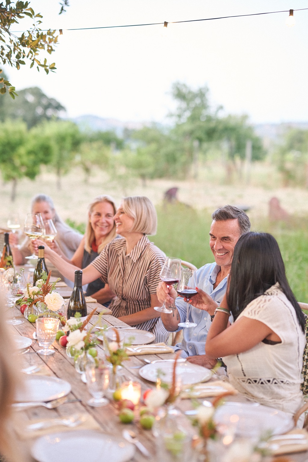 Guests toasting with wine at a long candlelit farm table at dusk, Sonoma County event photography