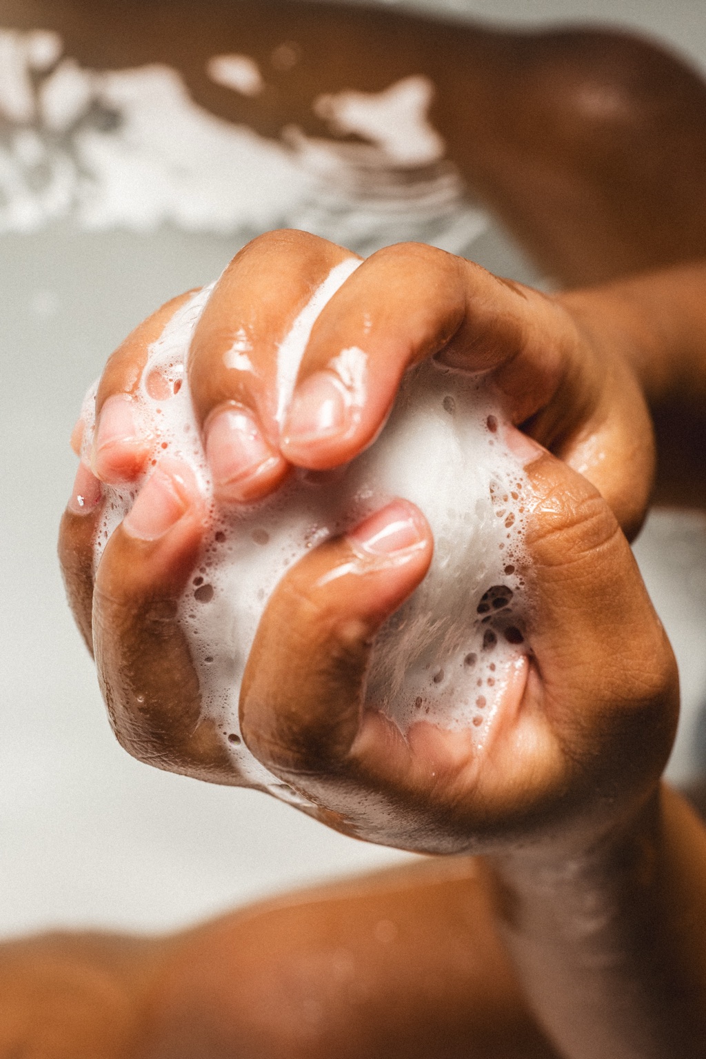 Close-up of a child's soapy hands squeezing lather in the bath, Frida Baby detail photography