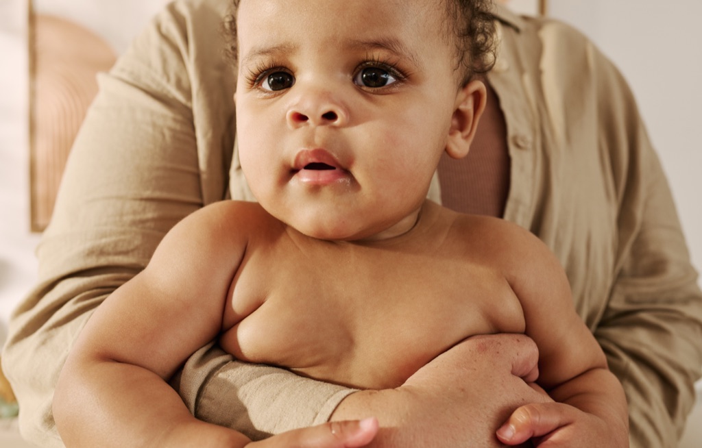 Close-up of a chubby-cheeked baby resting in a parent's arms, photographed for Frida