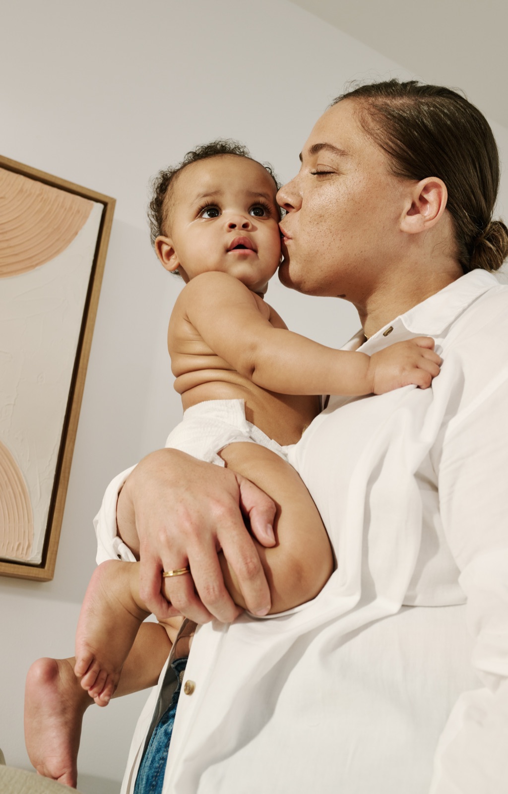 Detail of a lotion swirl on a baby's belly above the diaper line, Frida Baby product photography