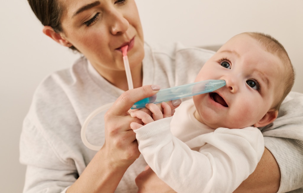 Mother using the NoseFrida nasal aspirator on her baby, Frida Baby campaign photography