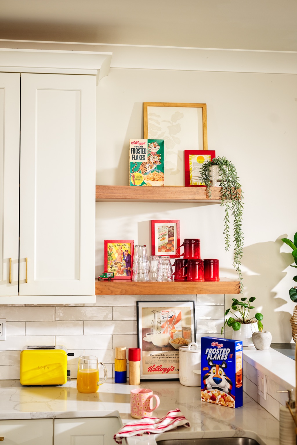 Kitchen set styled with vintage Frosted Flakes boxes and framed Kellogg's ads beside the modern box