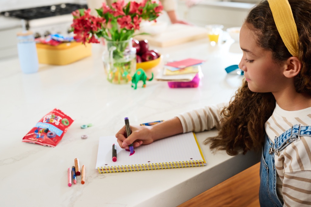 Girl coloring at the kitchen counter with a Froot Loops Jumbo Snax pack nearby, Kellogg's campaign photography by Dawn Heumann