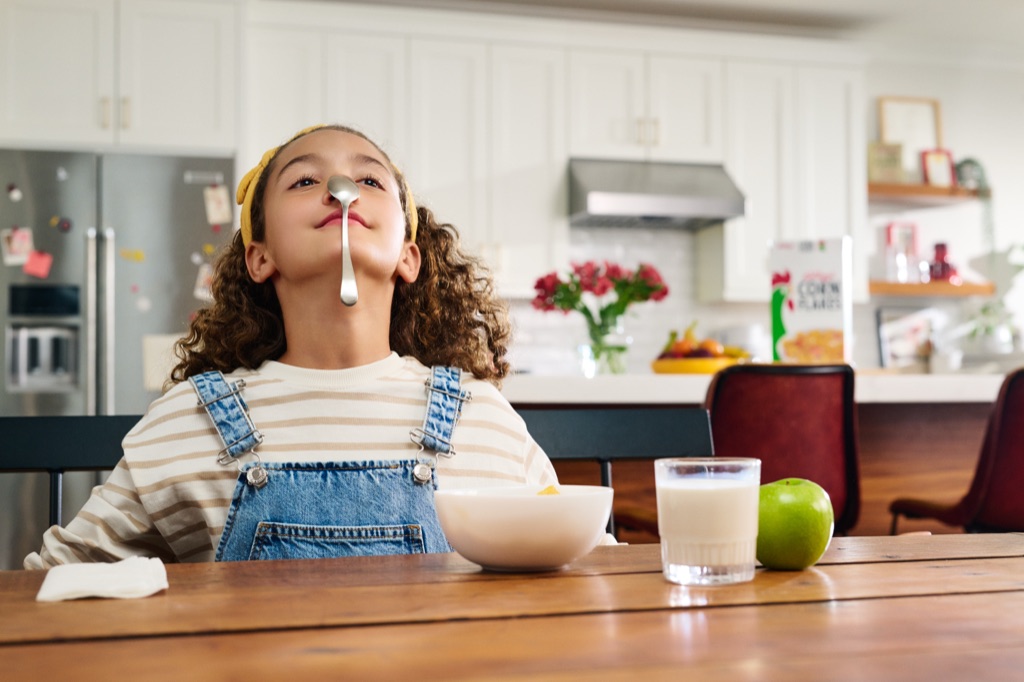Girl balancing a spoon on her nose over a bowl of Corn Flakes, Kellogg's campaign photography by Dawn Heumann