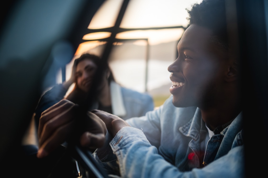 Smiling driver photographed through the roll cage of a vintage Bronco in warm sunset light